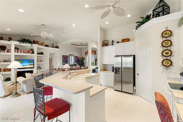 kitchen with light tile patterned flooring, white cabinetry, a kitchen bar, ceiling fan, and stainless steel fridge