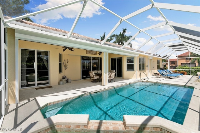 view of pool featuring ceiling fan, glass enclosure, and a patio