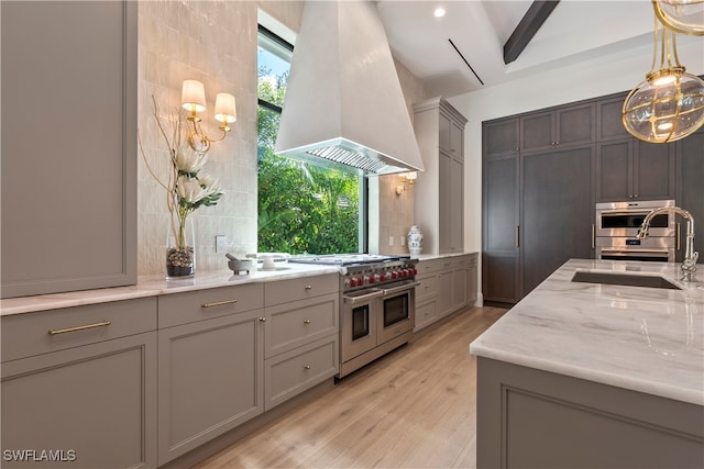 kitchen featuring light wood-type flooring, beamed ceiling, sink, island range hood, and appliances with stainless steel finishes