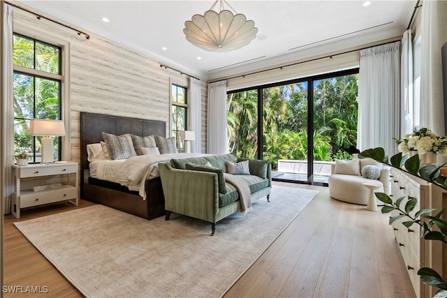 bedroom featuring hardwood / wood-style flooring, crown molding, and access to exterior