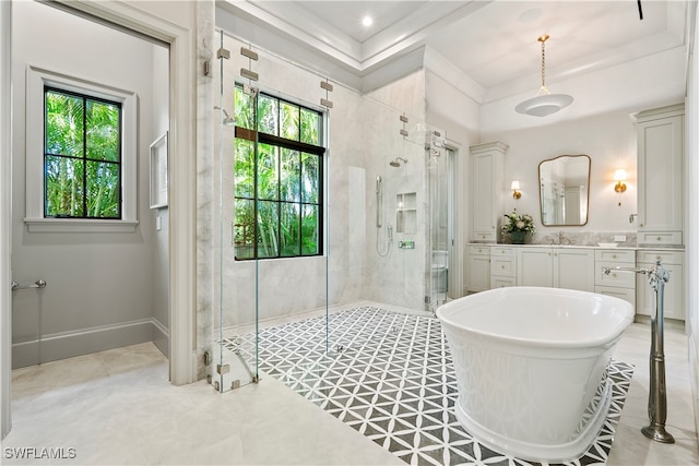 bathroom featuring plus walk in shower, vanity, a raised ceiling, and a healthy amount of sunlight