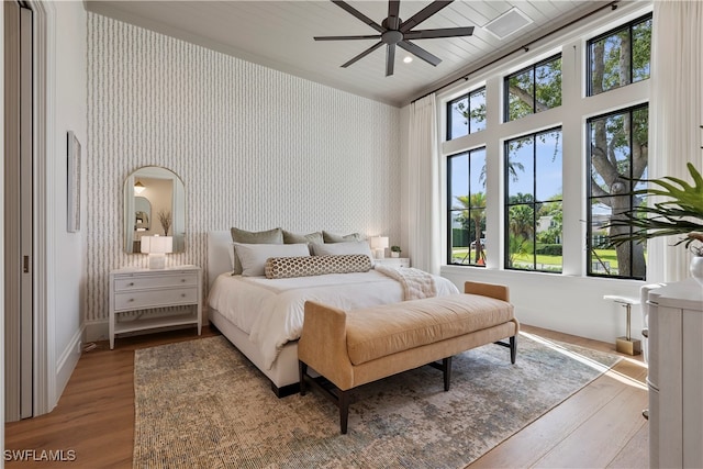 bedroom with ceiling fan, hardwood / wood-style floors, and multiple windows