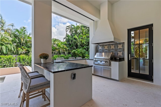 kitchen featuring exhaust hood, a breakfast bar area, sink, and kitchen peninsula