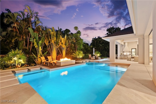 pool at dusk featuring a patio area