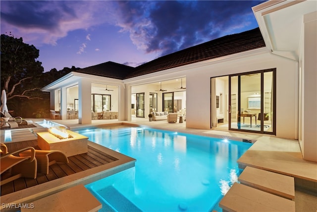 pool at dusk with a patio and an outdoor fire pit