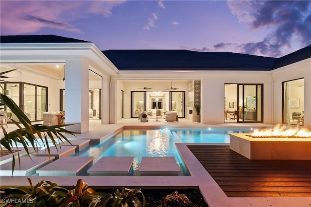 pool at dusk featuring a patio and a fire pit