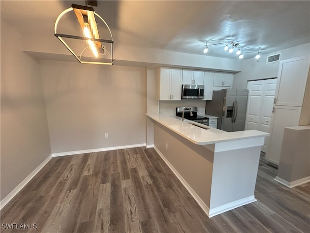 kitchen featuring white cabinetry, kitchen peninsula, sink, dark wood-type flooring, and appliances with stainless steel finishes