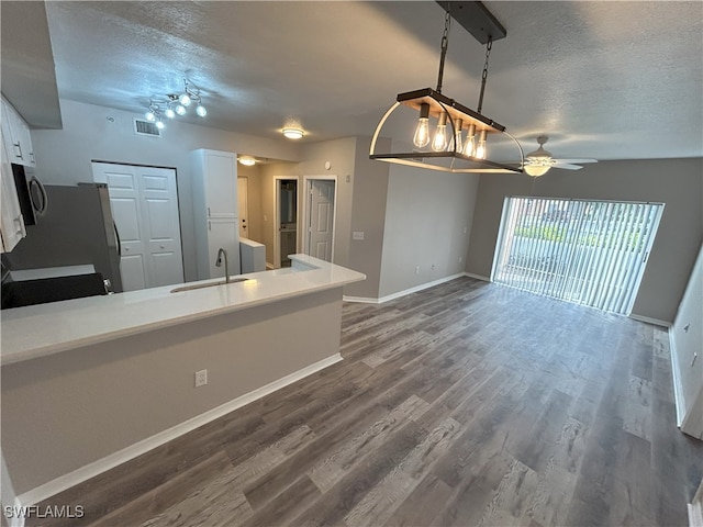 kitchen with a textured ceiling, dark wood-type flooring, sink, and white cabinets