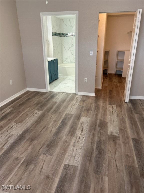 unfurnished bedroom with connected bathroom and hardwood / wood-style floors