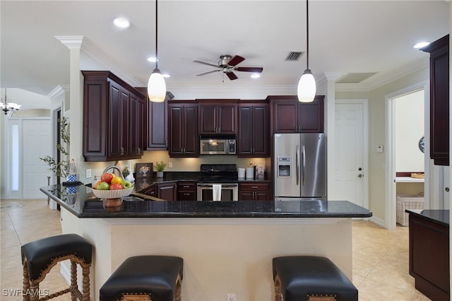 kitchen featuring hanging light fixtures, ceiling fan with notable chandelier, kitchen peninsula, a breakfast bar, and appliances with stainless steel finishes