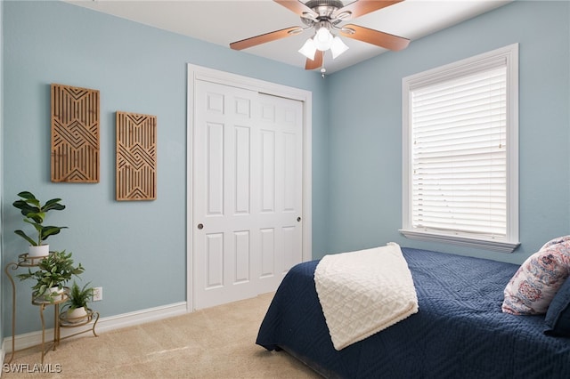 bedroom with light colored carpet, ceiling fan, and a closet