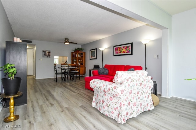 living room with ceiling fan, hardwood / wood-style flooring, and a textured ceiling