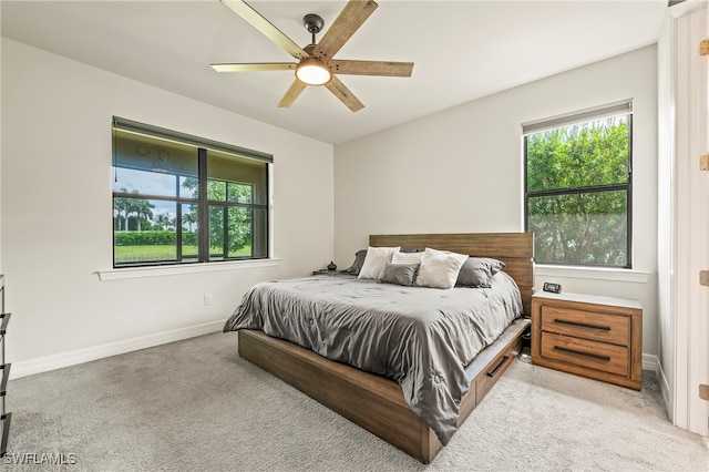 bedroom with multiple windows, ceiling fan, and light colored carpet