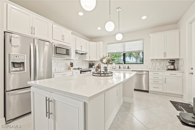 kitchen with decorative backsplash, white cabinetry, stainless steel appliances, a center island, and decorative light fixtures