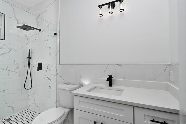 bathroom with vanity, toilet, and a tile shower