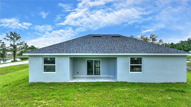 rear view of house featuring a lawn and a water view