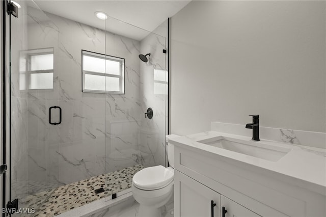 bathroom featuring a shower with shower door, toilet, and vanity