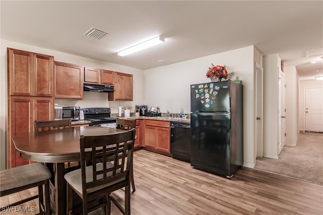 kitchen with black appliances and light hardwood / wood-style flooring