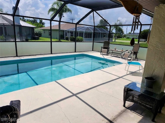 view of swimming pool featuring glass enclosure, a patio area, and a yard