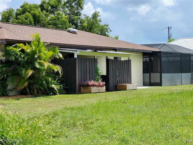 back of house featuring a lanai and a yard