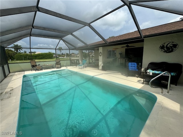 view of pool with glass enclosure, a patio, and ceiling fan