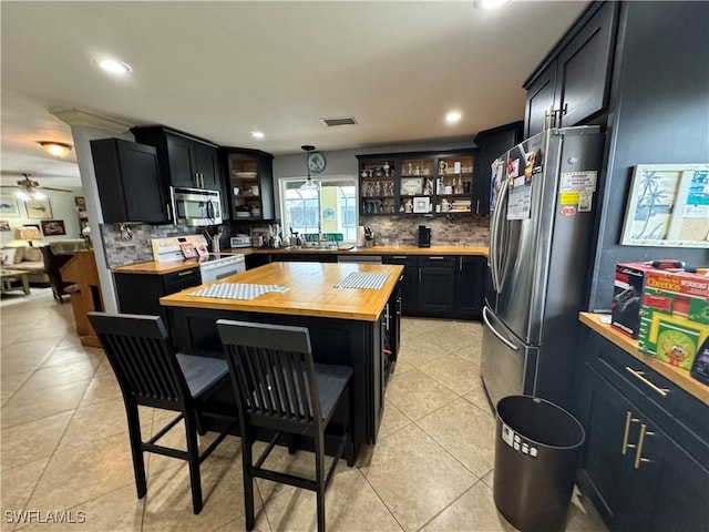 kitchen featuring stainless steel appliances, a center island, tasteful backsplash, and butcher block countertops