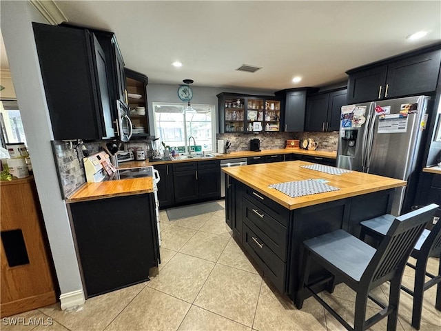 kitchen with a center island, wooden counters, decorative backsplash, hanging light fixtures, and light tile patterned floors