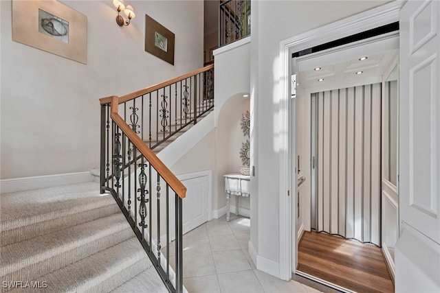 stairs with a towering ceiling and hardwood / wood-style floors