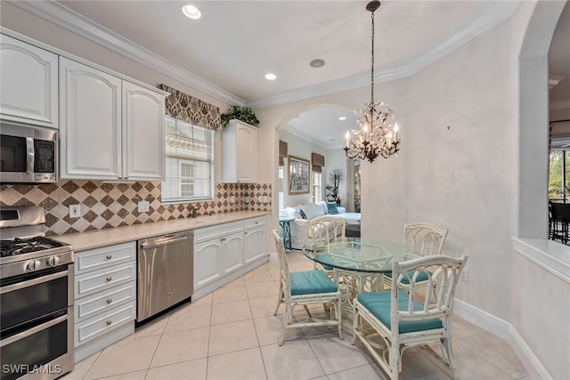 kitchen featuring stainless steel appliances, white cabinets, a wealth of natural light, and decorative light fixtures