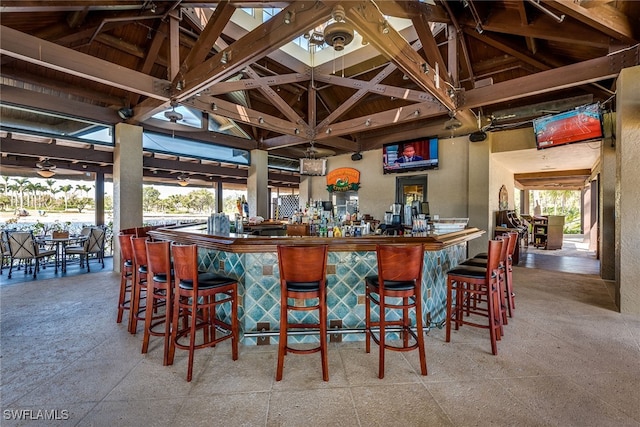 bar featuring ceiling fan, lofted ceiling, and a healthy amount of sunlight