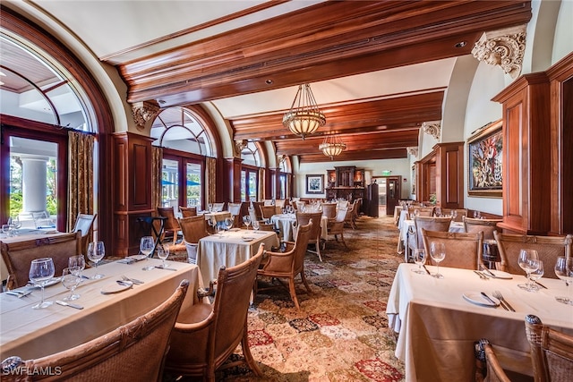 dining space with ornate columns, a notable chandelier, beamed ceiling, and a wealth of natural light