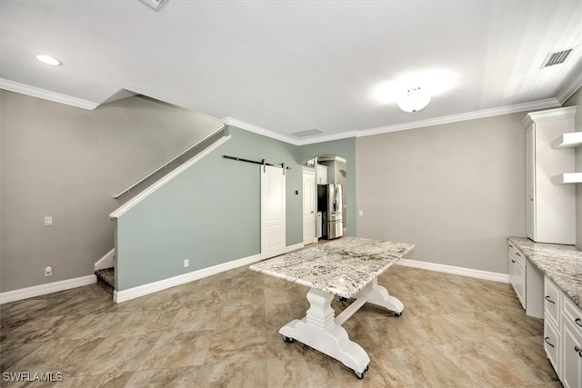 unfurnished dining area with a barn door and ornamental molding