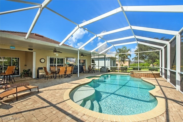 view of swimming pool featuring glass enclosure, a patio, ceiling fan, and an in ground hot tub