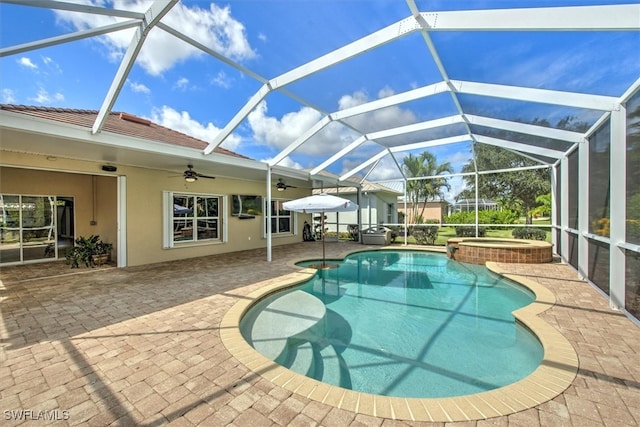 view of pool with glass enclosure, ceiling fan, a patio, and an in ground hot tub