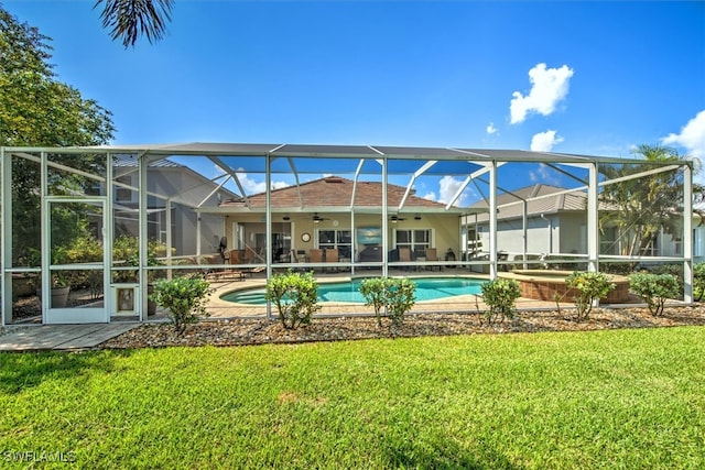 back of property with a yard, a lanai, a patio area, and a pool with hot tub