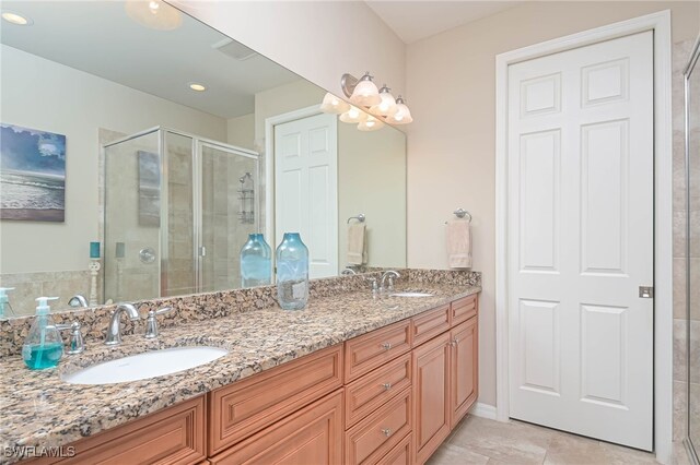 bathroom featuring tile patterned flooring, a shower with shower door, and vanity