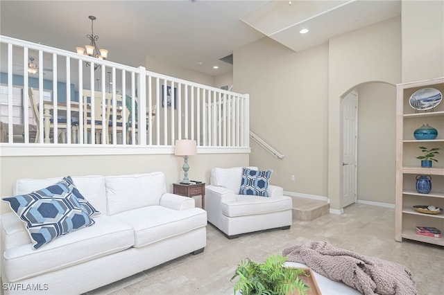 living room with built in shelves, a notable chandelier, and a towering ceiling