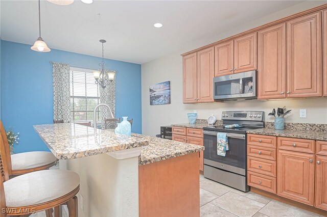 kitchen with appliances with stainless steel finishes, light stone countertops, a chandelier, a kitchen bar, and a kitchen island with sink