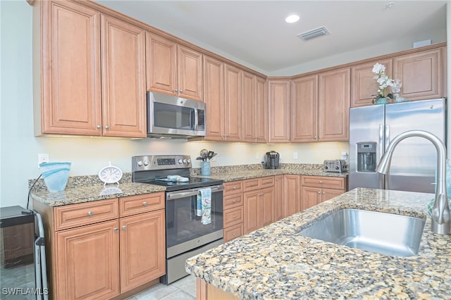 kitchen with light stone counters, stainless steel appliances, and sink