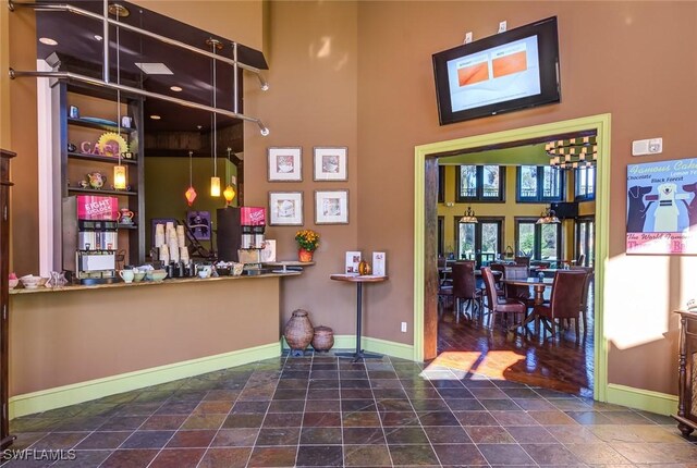 bar featuring a towering ceiling and dark hardwood / wood-style flooring