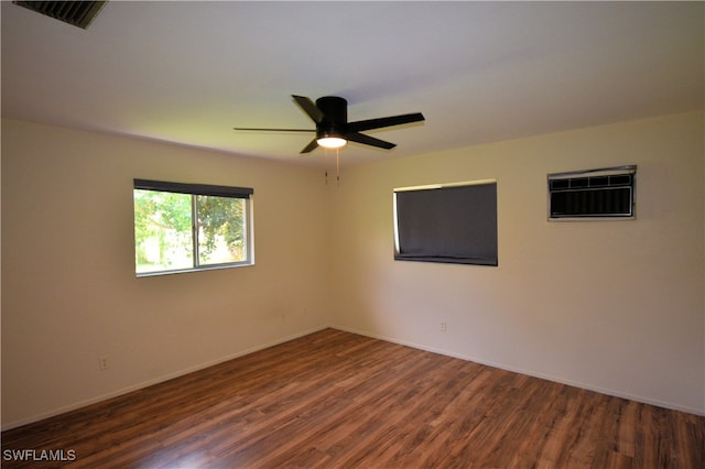 empty room featuring dark wood-type flooring, a wall mounted air conditioner, and ceiling fan