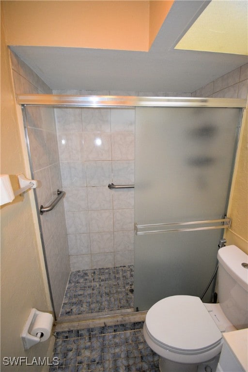 bathroom with toilet and a shower with door