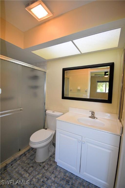 bathroom featuring vanity, toilet, and a shower with door