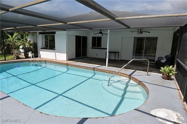 view of pool with glass enclosure, ceiling fan, and a patio