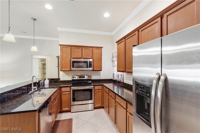 kitchen with dark stone counters, crown molding, sink, hanging light fixtures, and stainless steel appliances