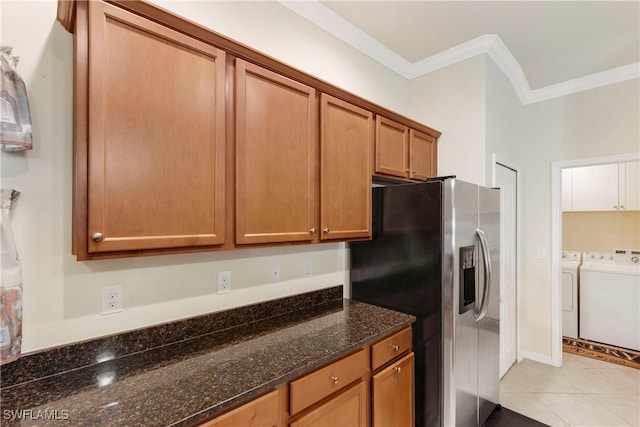 kitchen featuring stainless steel fridge with ice dispenser, dark stone countertops, crown molding, light tile patterned floors, and washer and dryer