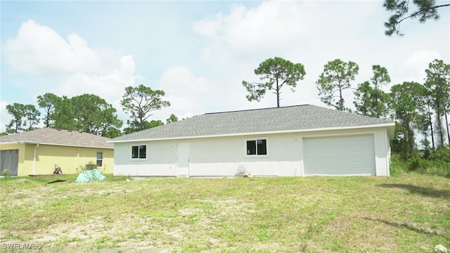 rear view of house featuring a garage and a yard