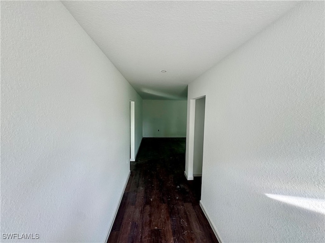 hall with a textured ceiling and dark hardwood / wood-style flooring