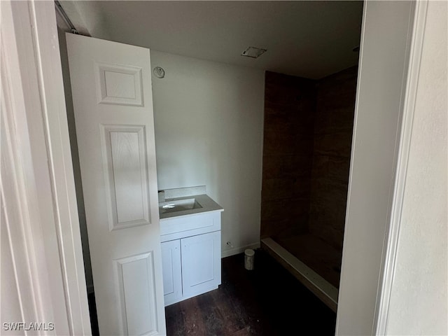 bathroom with hardwood / wood-style floors, walk in shower, and vanity