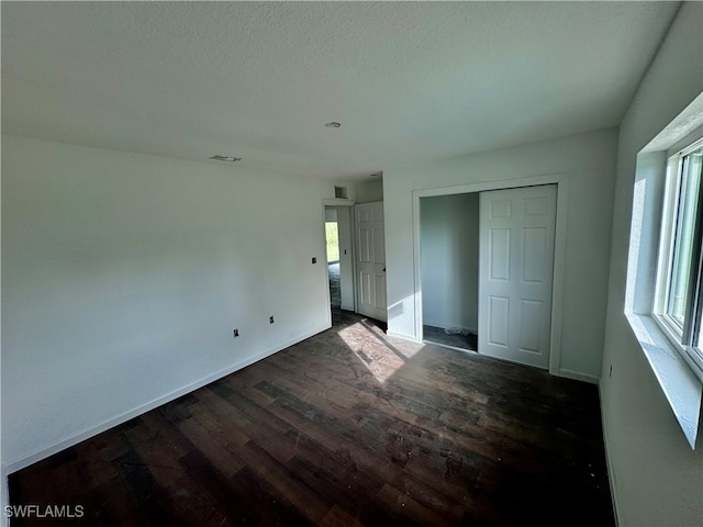 unfurnished bedroom with a closet and dark wood-type flooring